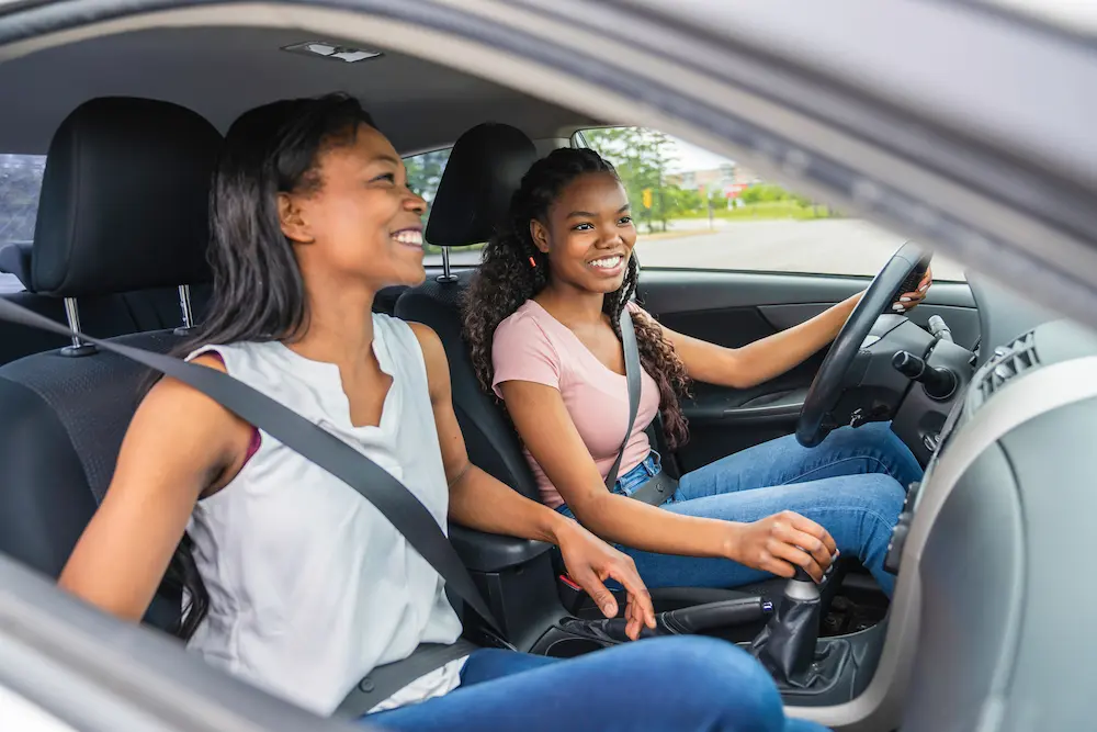 Young teenage driver seated in her new car with her parent after buying a car