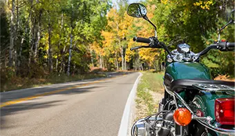Beautiful autumn day with trees and open road and motorcycle financed with motorcycle loan by People’s Community Federal Credit Union