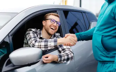 man shakes hand with salesman after getting financing for used car 