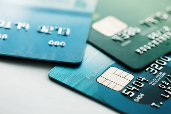 A stack of four three cards in various blue & green colors on a table.